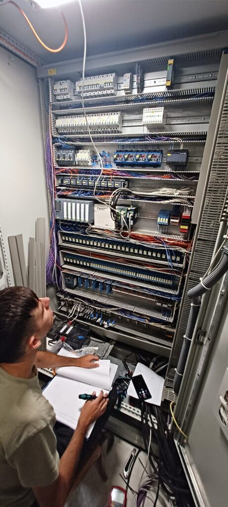 Engineer working with wiring diagrams inside industrial control cabinet for power plant control system and automation equipment